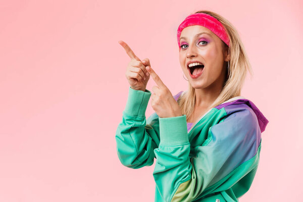 Image of delighted young woman pointing fingers aside at copyspace