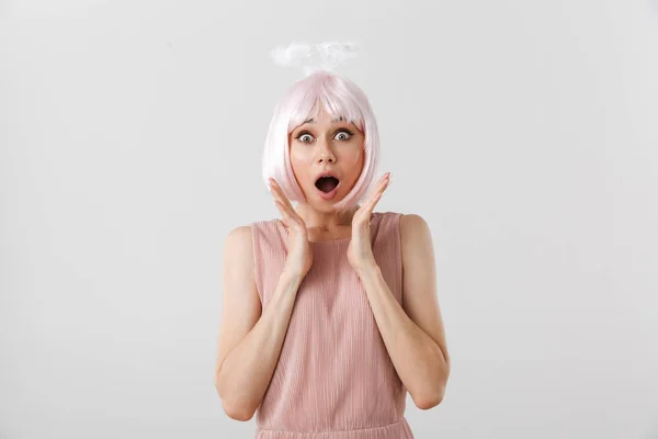 Πορτρέτο της ενθουσιασμένος έκπληκτος γυναίκα φορώντας ροζ περούκα και παιχνίδι φωτοστέφανο κοιτάζοντας κάμερα, ενώ ξερνώντας τα χέρια — Φωτογραφία Αρχείου