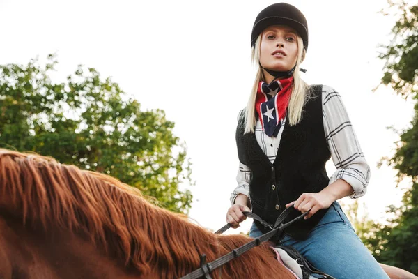 Image of pretty woman wearing hat riding horse at yard in countr — Stock Photo, Image