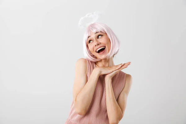 Retrato de mulher encantadora feliz vestindo peruca rosa e halo de brinquedo olhando para o copyspace enquanto sorri — Fotografia de Stock