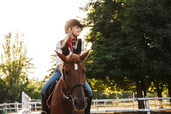 Изображение молодой женщины в шляпе верхом на лошади во дворе в стране — стоковое фото
