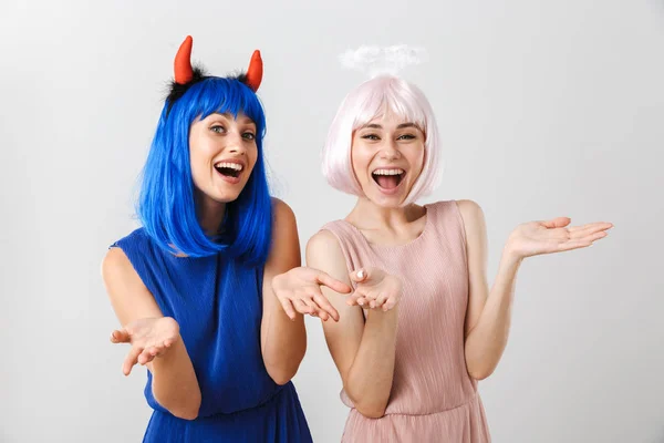 Porträt zweier netter, glücklicher Frauen mit Teufelshörnern und Heiligenschein, die in die Kamera lachen — Stockfoto