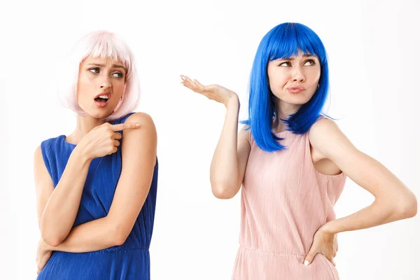 Retrato de dos mujeres disgustadas con pelucas azules y rosadas sosteniendo y señalando con el dedo el espacio de copia — Foto de Stock