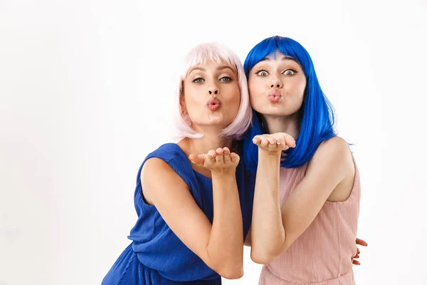 Porträt zweier verführerischer Frauen mit blauen und rosa Perücken, die Luftküsse vor der Kamera schleifen — Stockfoto