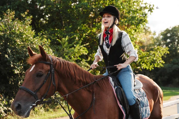 Imagem da bela mulher usando chapéu equitação cavalo no quintal em cou — Fotografia de Stock
