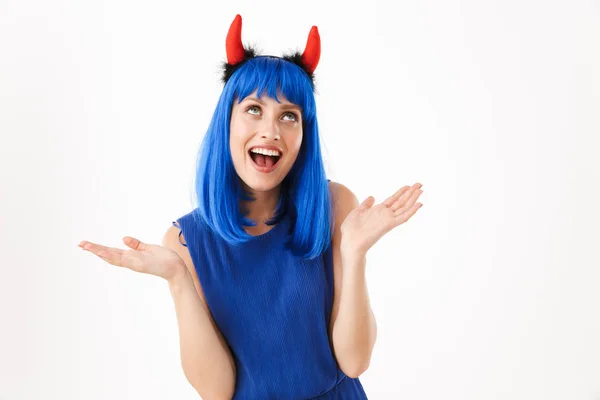 Porträtt av glad kvinna bär blå peruk och leksak djävulen horn tittar uppåt medan spyr upp händer — Stockfoto