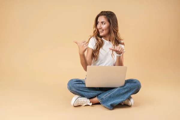 Obrázek atraktivní ženy sedící na podlaze se stříbrným laptopem — Stock fotografie