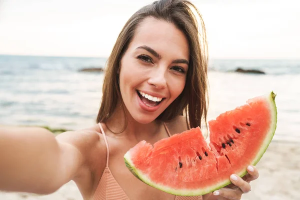 Image of delighted woman eating watermelon and taking selfie photo — Stock Photo, Image