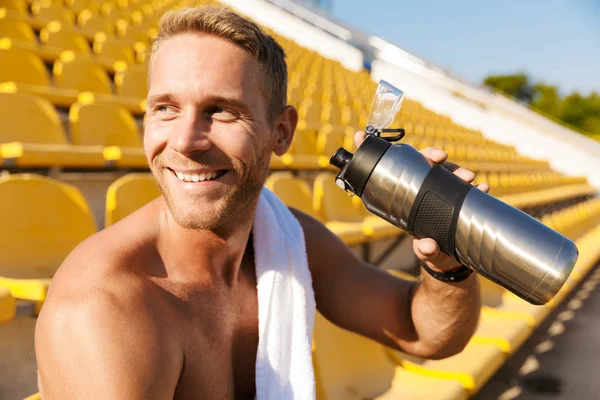 Obrázek šťastného sportovce bez trička pitná voda na stadionu moře — Stock fotografie