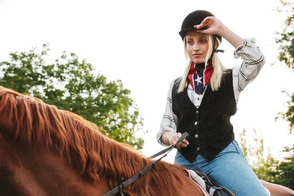 Imagem de mulher adorável usando chapéu equitação cavalo no quintal no sofá — Fotografia de Stock