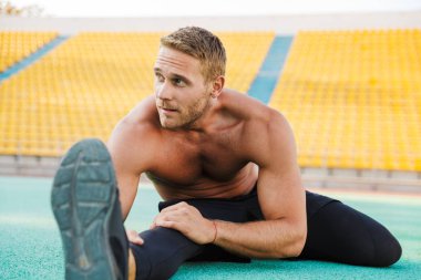 Spor salonunda vücudunu esneten yakışıklı bir adam resmi.