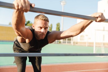 Ciddi bir sporcunun, sta 'da metal korkuluklarla antrenman yaparken görüntüsü