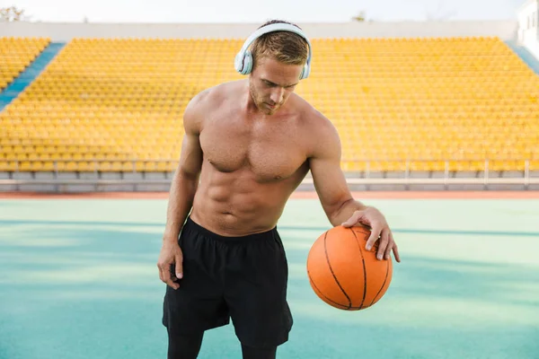 Obrázek muže ve sluchátkách, jak hraje basketbal na sportovním stadionu — Stock fotografie