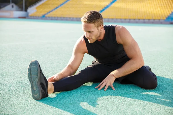 Imagem de um homem saudável a esticar o corpo em terreno desportivo outdoo — Fotografia de Stock