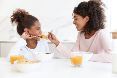 Amerikalı bir kadının kahvaltı yaparken kızını beslemesi.