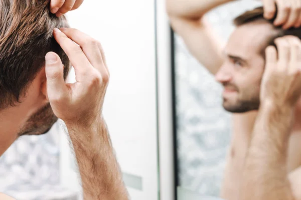 Preocupado jovem sem camisa homem examinando seu cabelo — Fotografia de Stock