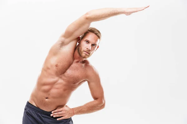 Handsome young concentrated sportsman doing stretching — Stock Photo, Image