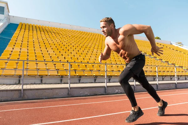 Image of shirtless sportsman running on track against stadium se