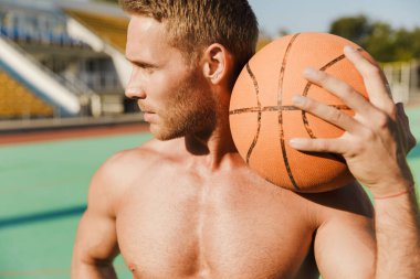 Stadyumda basketbolla poz veren sporcu..
