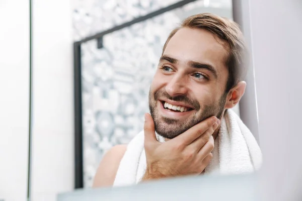 Щасливий молодий без сорочки чоловік дивиться на себе у ванній — стокове фото