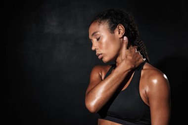 Spor giyimli rahat bir Amerikalı kadının boynuna dokunuşu.