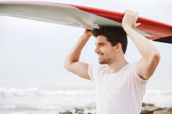 Handsome man surfer with surfing on a beach outside. — Stock Photo, Image