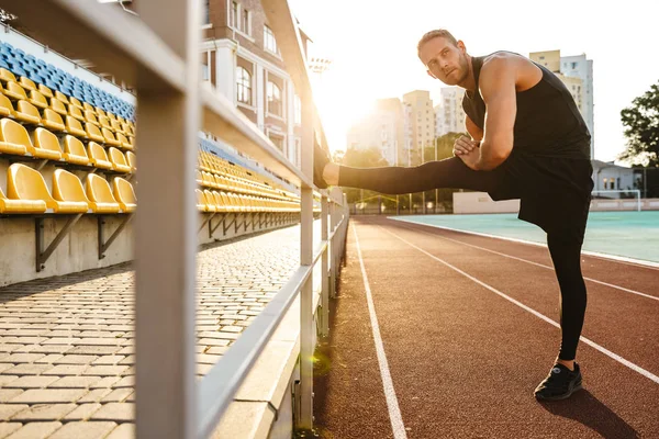 Jaki sport lubisz najbardziej? man make stretching exercises at stadium. — Zdjęcie stockowe