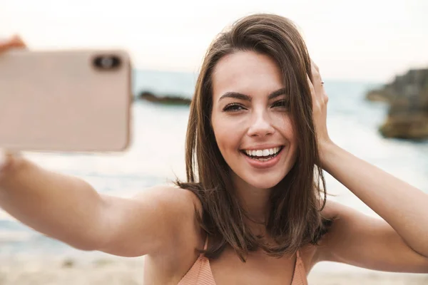 Imagen de una joven sonriente tomando una foto selfie en su celular —  Fotos de Stock