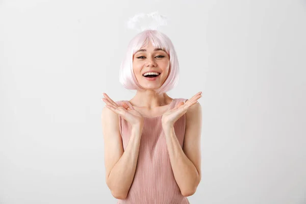 Retrato de mujer encantadora y complacida con peluca rosa y halo de juguete mirando a la cámara mientras vomita las manos —  Fotos de Stock