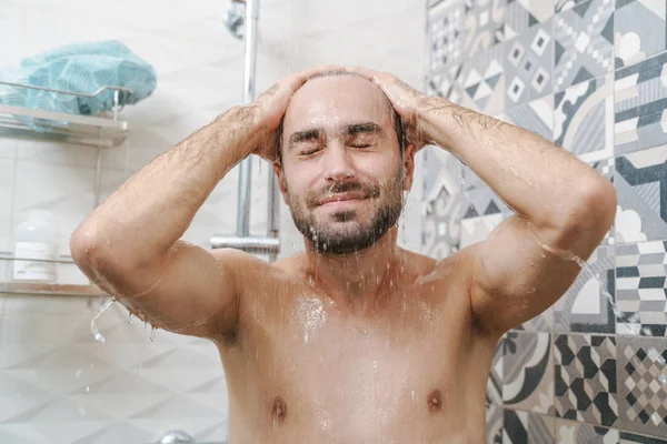 Atraktivní mladý usměvavý muž mytí vlasů — Stock fotografie