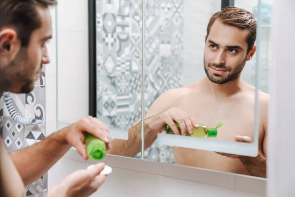 Hezký mladý muž bez trička, který se uchází o vodu po holení — Stock fotografie