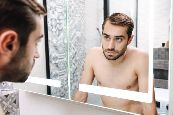 バスルームで自分自身を見て幸せな若い無気力な男 — ストック写真