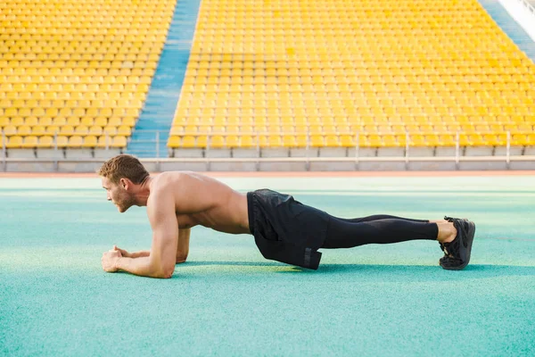 Imagen del hombre musculoso sin camisa haciendo ejercicio de tablón en deportes s — Foto de Stock
