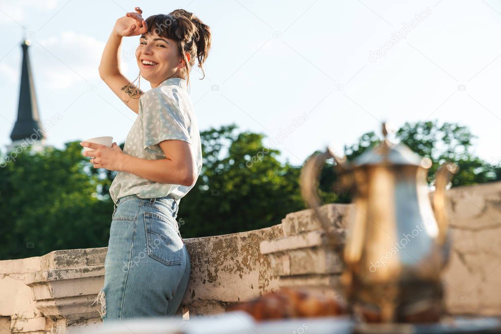 Young beautiful woman drinking coffee on a balcony.