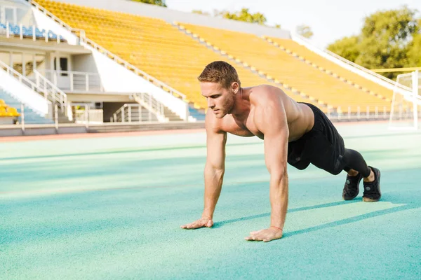 Imagen de un hombre fuerte sin camisa haciendo ejercicio de tablón en el personal deportivo — Foto de Stock