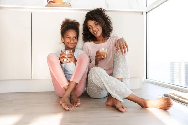 Улыбающаяся молодая мать и ее маленькая дочь в пижаме — стоковое фото