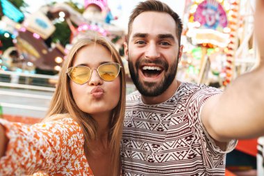 Sevgi dolu bir çift lunaparkta yürüyorlar.