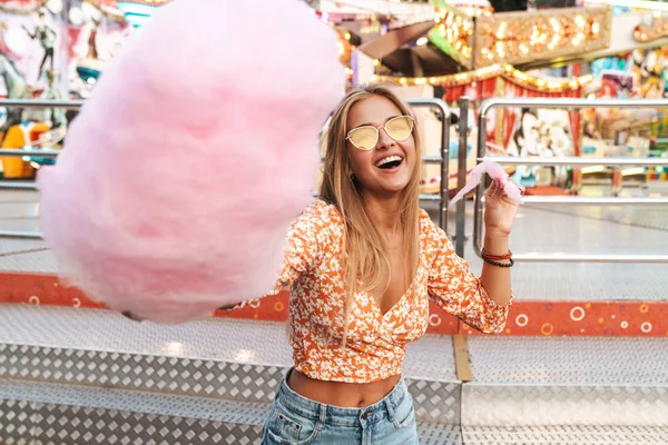 Woman walking outdoors in amusement park eat candyfloss. — Stock Photo, Image