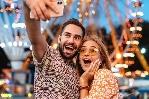 Positive loving couple walking outdoors in amusement park — Stock Photo, Image