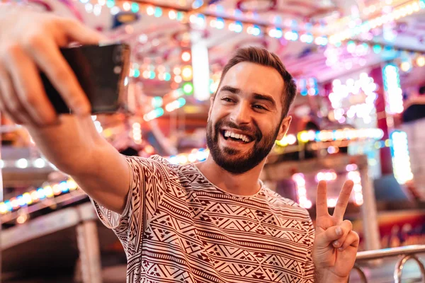 Lächelnder fröhlicher Mann, der draußen herumläuft, macht Selfie — Stockfoto