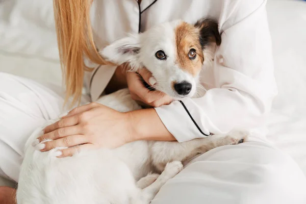 Meisje in pyjama thuis op bed met haar hond knuffelen. — Stockfoto