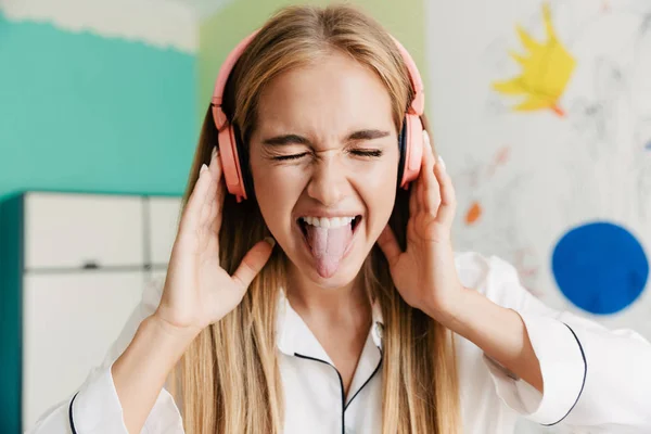 Linda chica en pijama en casa escuchando música con auriculares . —  Fotos de Stock