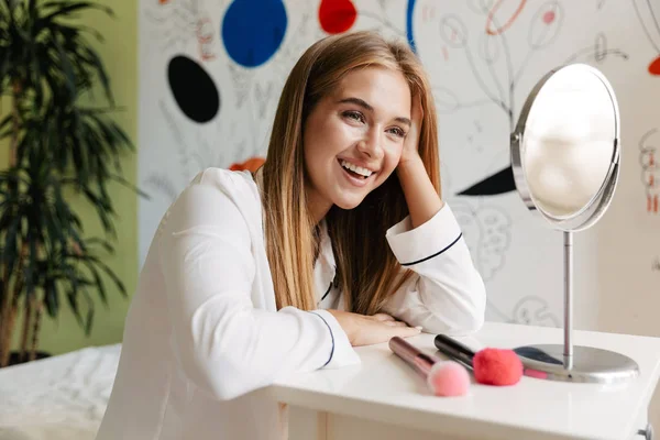 Jolie fille en pyjama à la maison près du miroir avec brosse de maquillage . — Photo