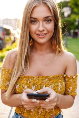 Güzel sarışın kız cep telefonu kullanıyor.