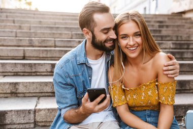 Gülümseyen genç çift merdivenlerde birlikte oturuyor.