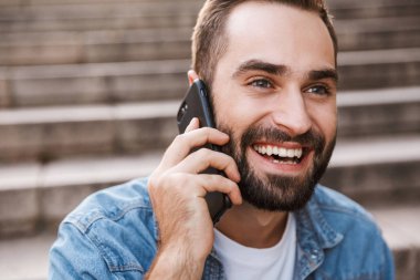 cep telefonu kullaranarak gülümseyen genç adam