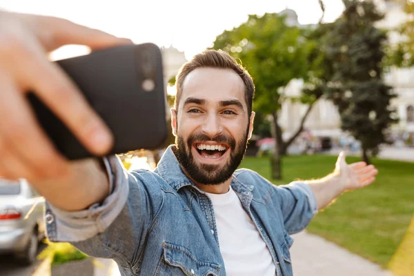 陽気な笑顔若いです男取りますAセルフィーとともに携帯電話 — ストック写真