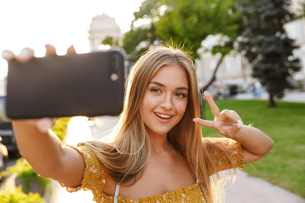 Linda sorridente jovem loira menina tomando uma selfie — Fotografia de Stock