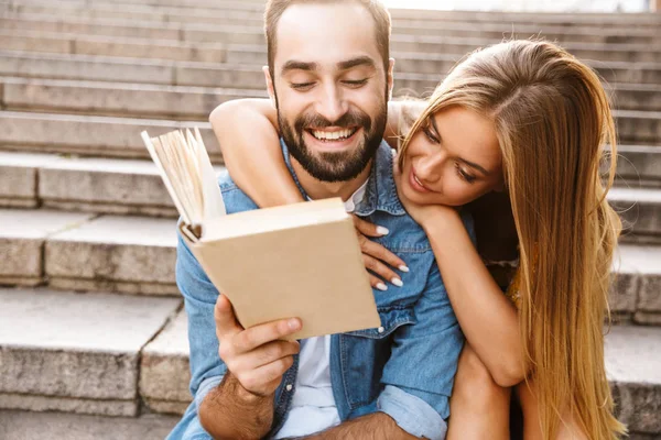 Sorridente bella giovane coppia seduta insieme sulle scale — Foto Stock