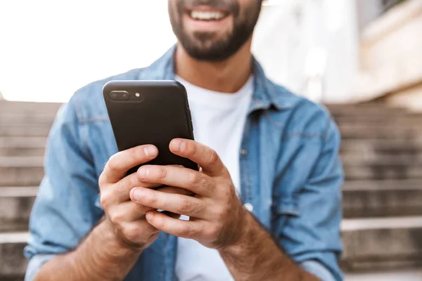 Usmívající se mladý muž pomocí mobilního telefonu — Stock fotografie